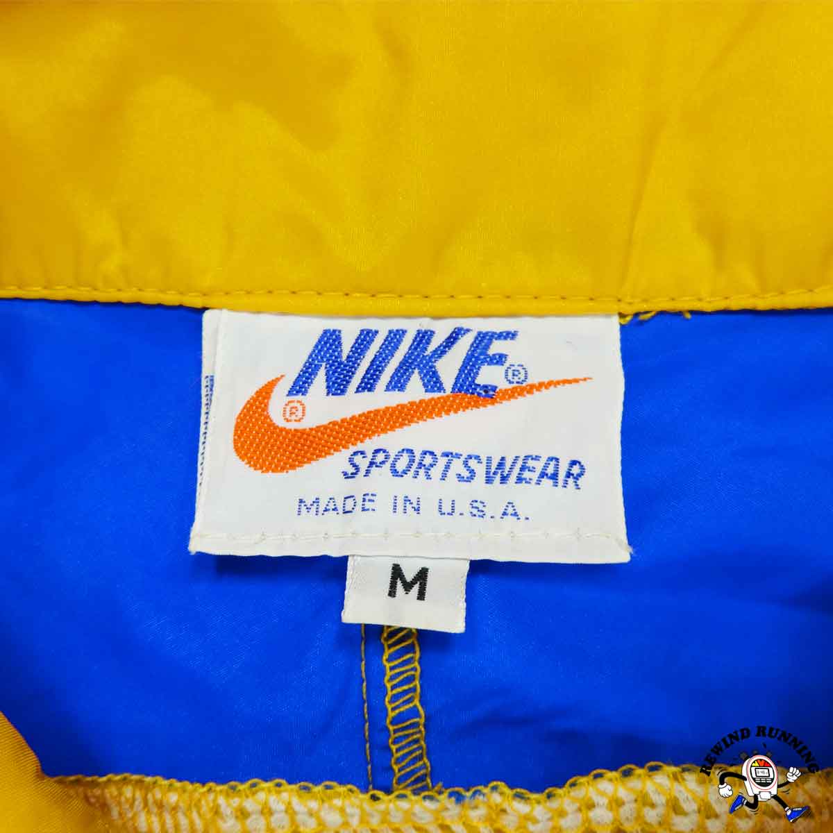 Close-up of a Nike Sportswear label on a yellow and blue garment.