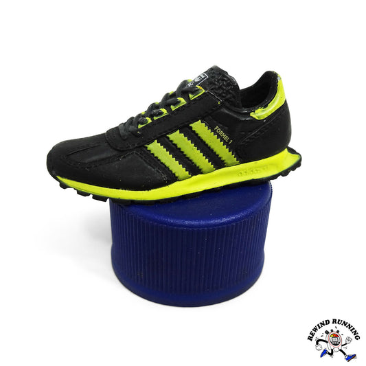 Black and yellow adidas Formel 1 sneaker running shoe on a blue pepsi soda bottle cap with a brand logo in the corner.