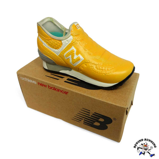 Yellow New Balance 576 sneaker candle on a cardboard box with brand logo