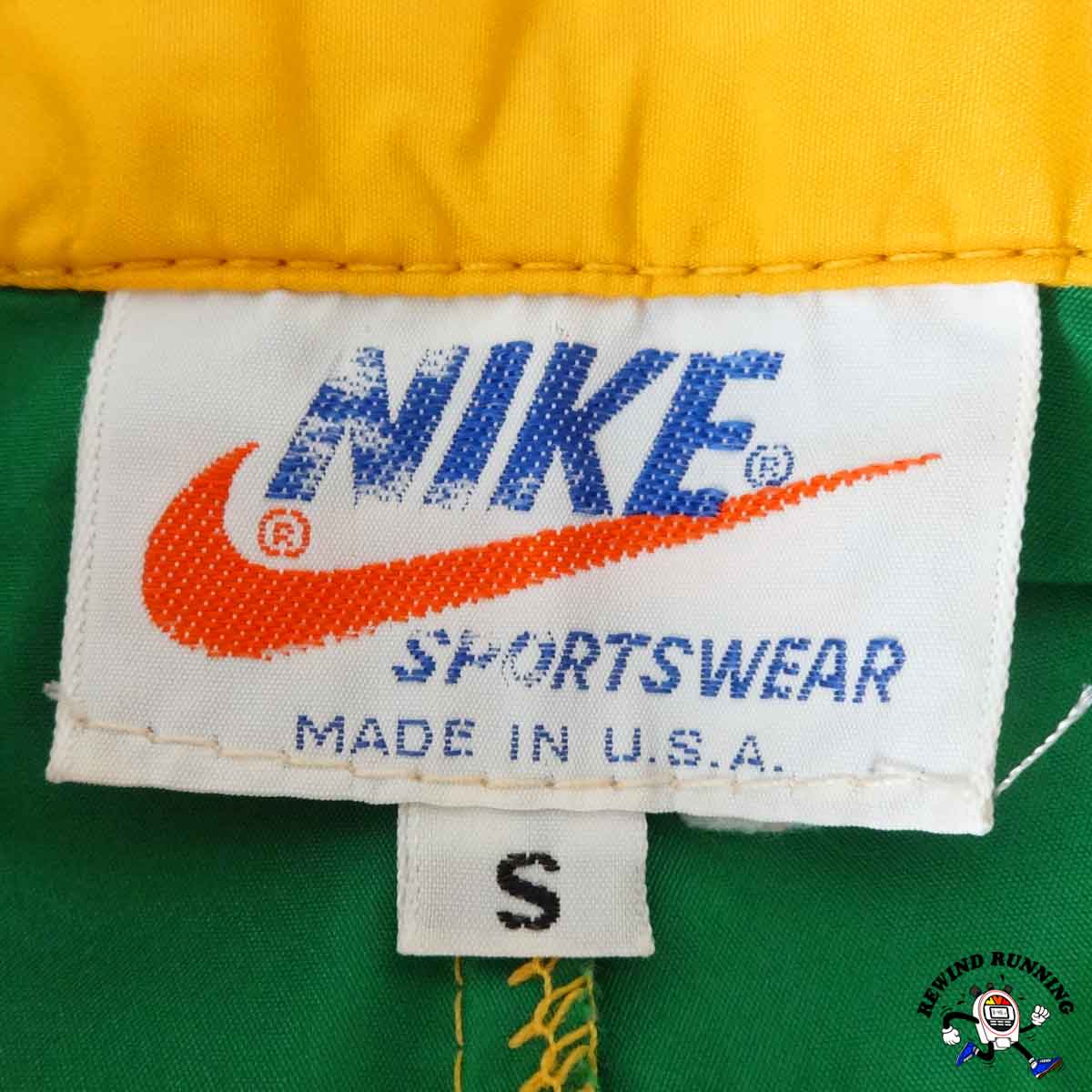 Close-up of a Nike Sportswear label on a garment with a green background.