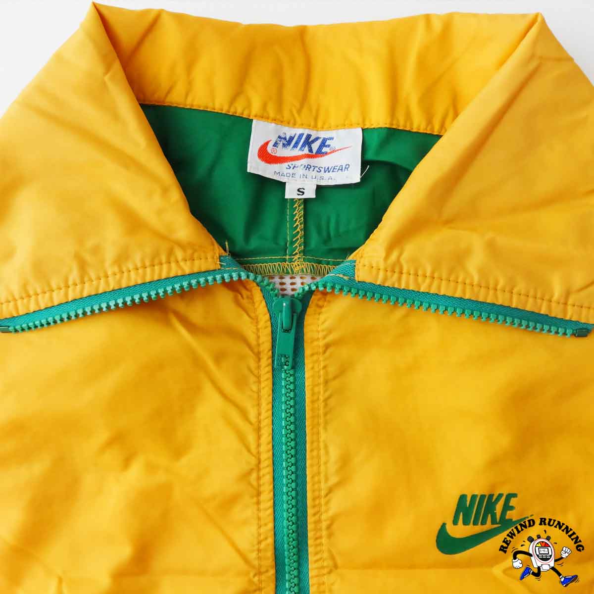 Yellow jacket with green zipper and Nike branding on a white background