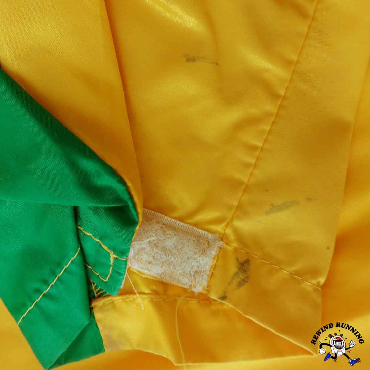 Close-up of a yellow and green fabric with a visible brand logo in the corner.