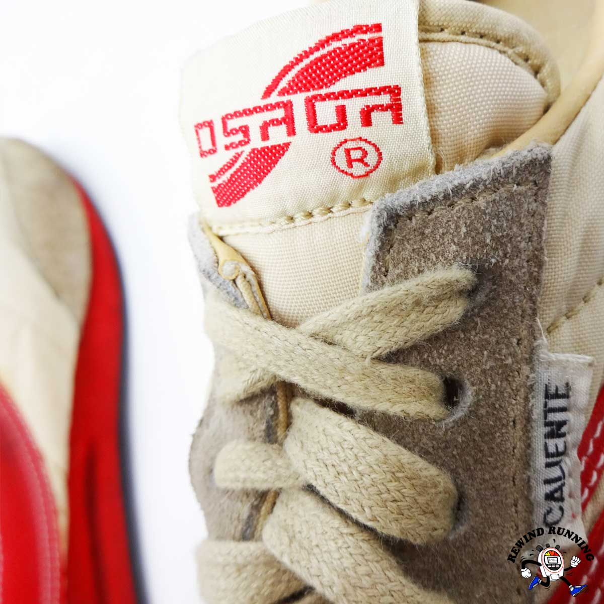 Close-up of a beige sneaker with red branding on a white background. The image displays vintage tongue and branding labels for the Osaga Caliente shoes.